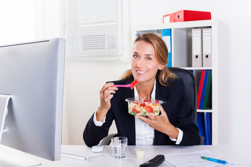 Smiling woman eating at desk